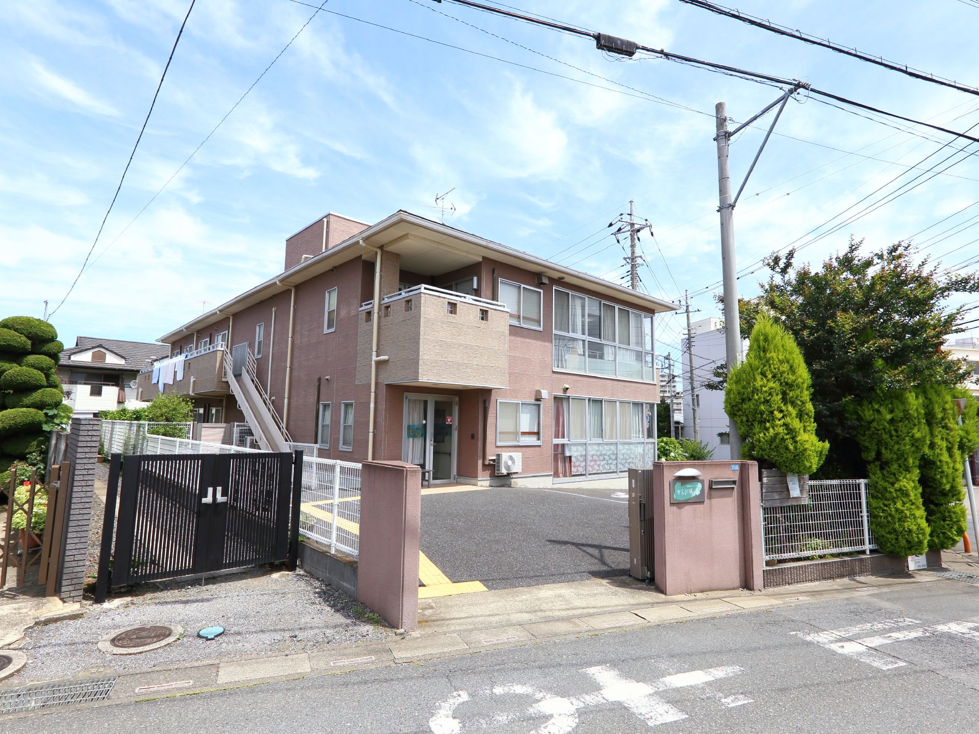 閑静な住宅街の中にある、アパートのような二階建ての当施設。一階、二階共に大きな窓が外からも見える。送迎の車も出入りしやすい。