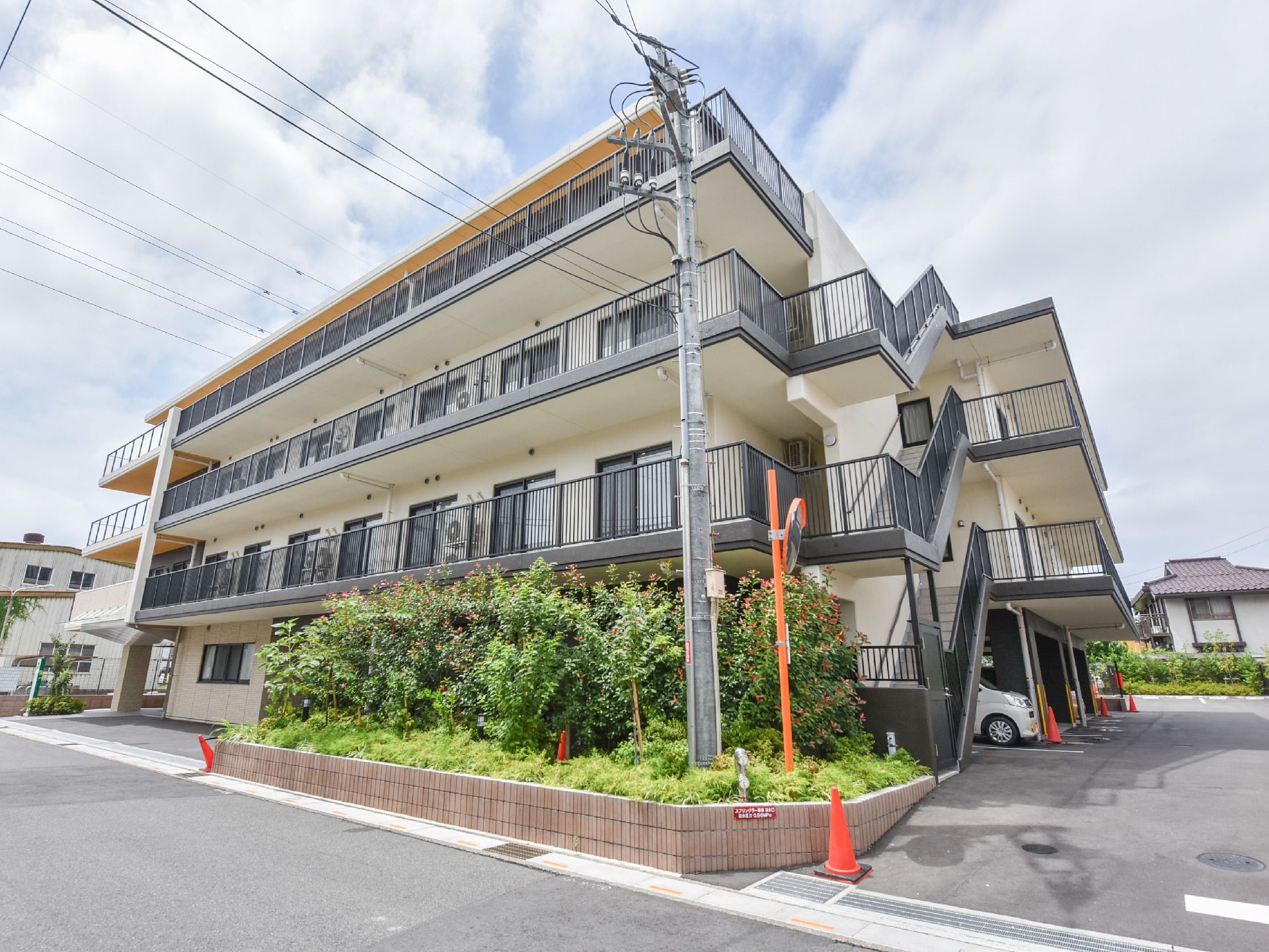 施設は4階建ての建物である。右側には各階に通じる外階段が設けられている。前面には植え込みがあり、角部分にはカーブミラーがある。