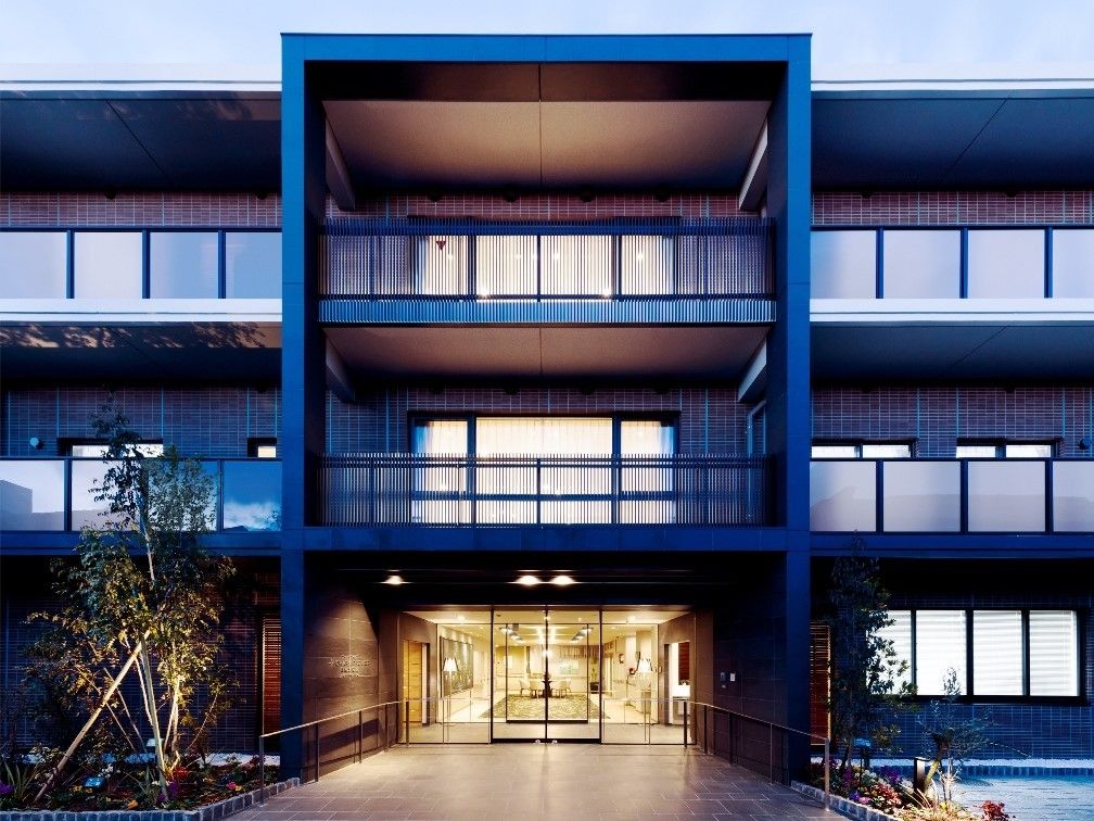 ３階建てのスタイリッシュな外観のグループホームである。入口の両サイドには、色とりどりの花や草木が植えられている。