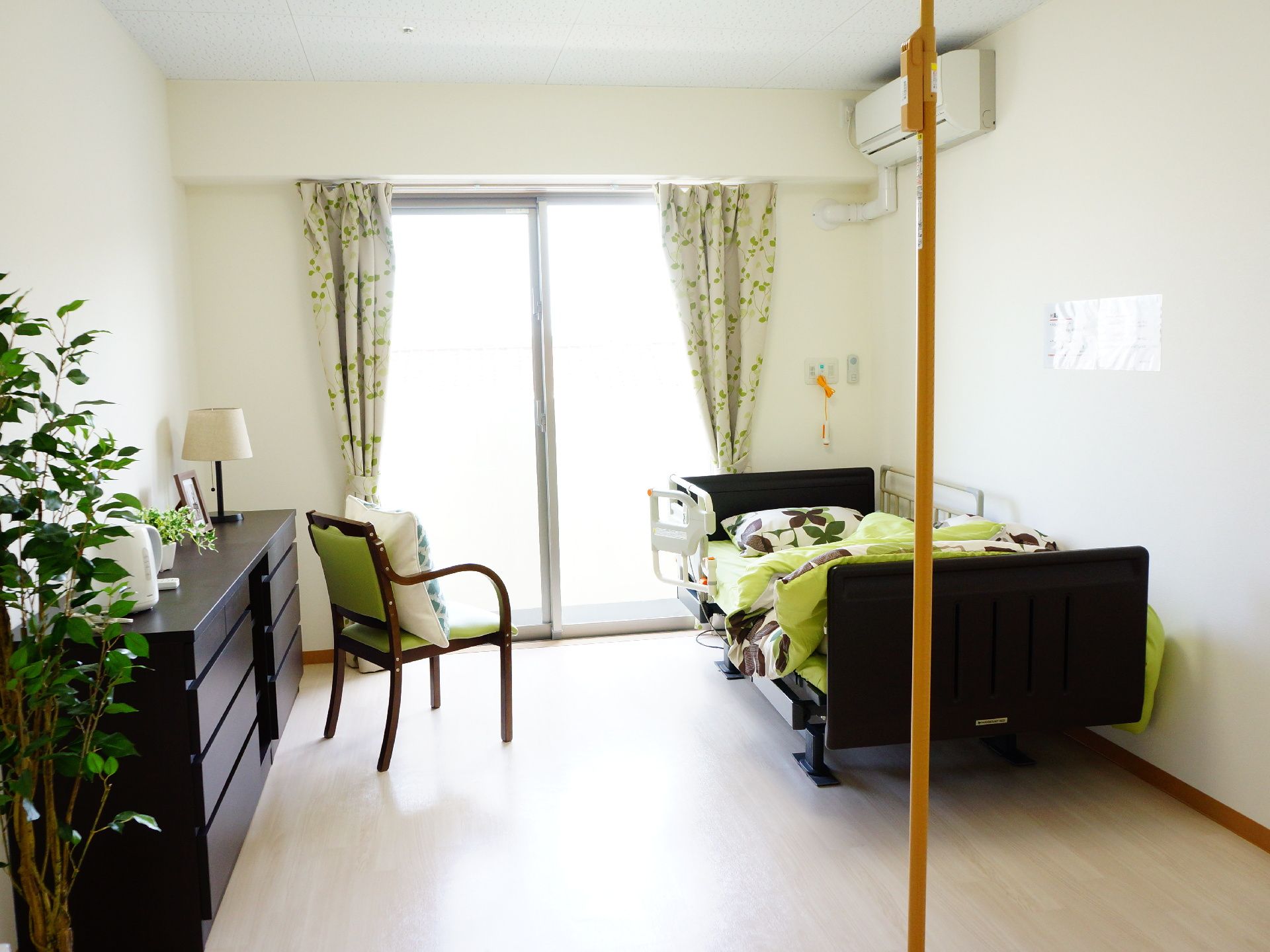 部屋には大きな窓があり明るい。備え付けのベット・椅子・棚はこげ茶色で統一され落ち着いた部屋となっている。