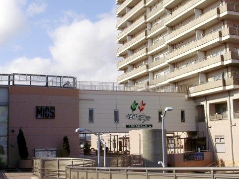 白い壁に施設の名前と鮮やかな彩りのシンボルマークが大きく描かれている。すぐ横には高層マンションがある。