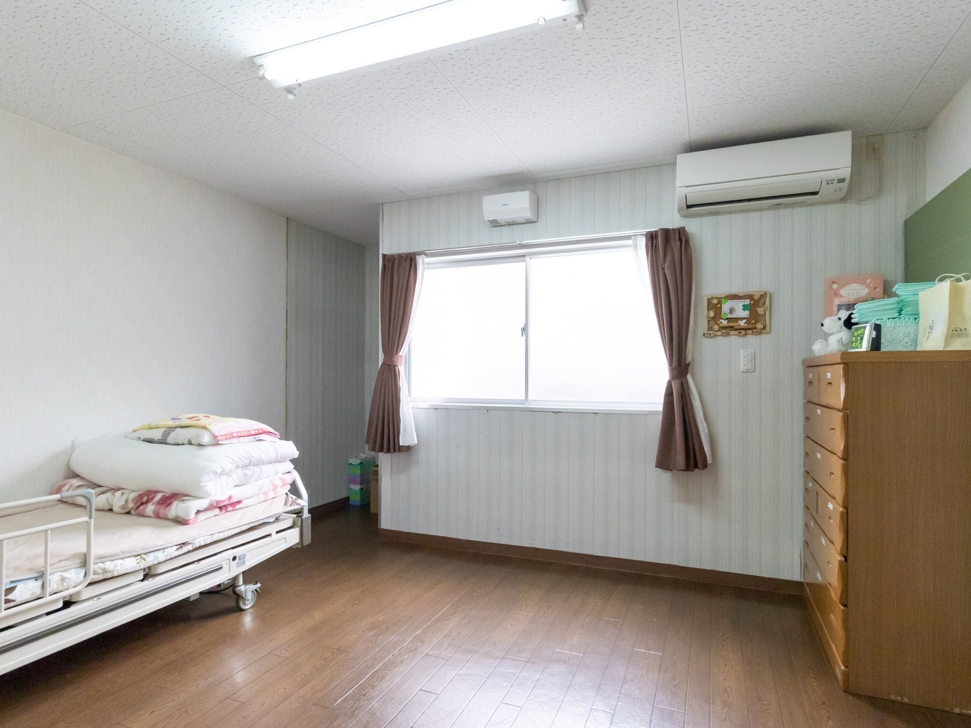 居室の壁際にベッドがあり、反対側の壁際にタンスが置いてある。間には広いスペースがあり、テーブルや椅子を置くこともできる。