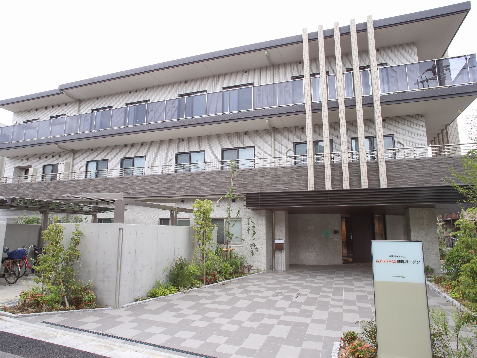 3階建のモダンな建物。エントランスまでは平面状なので車いすや杖をつきながらの移動が楽。そばに自転車置場がある。