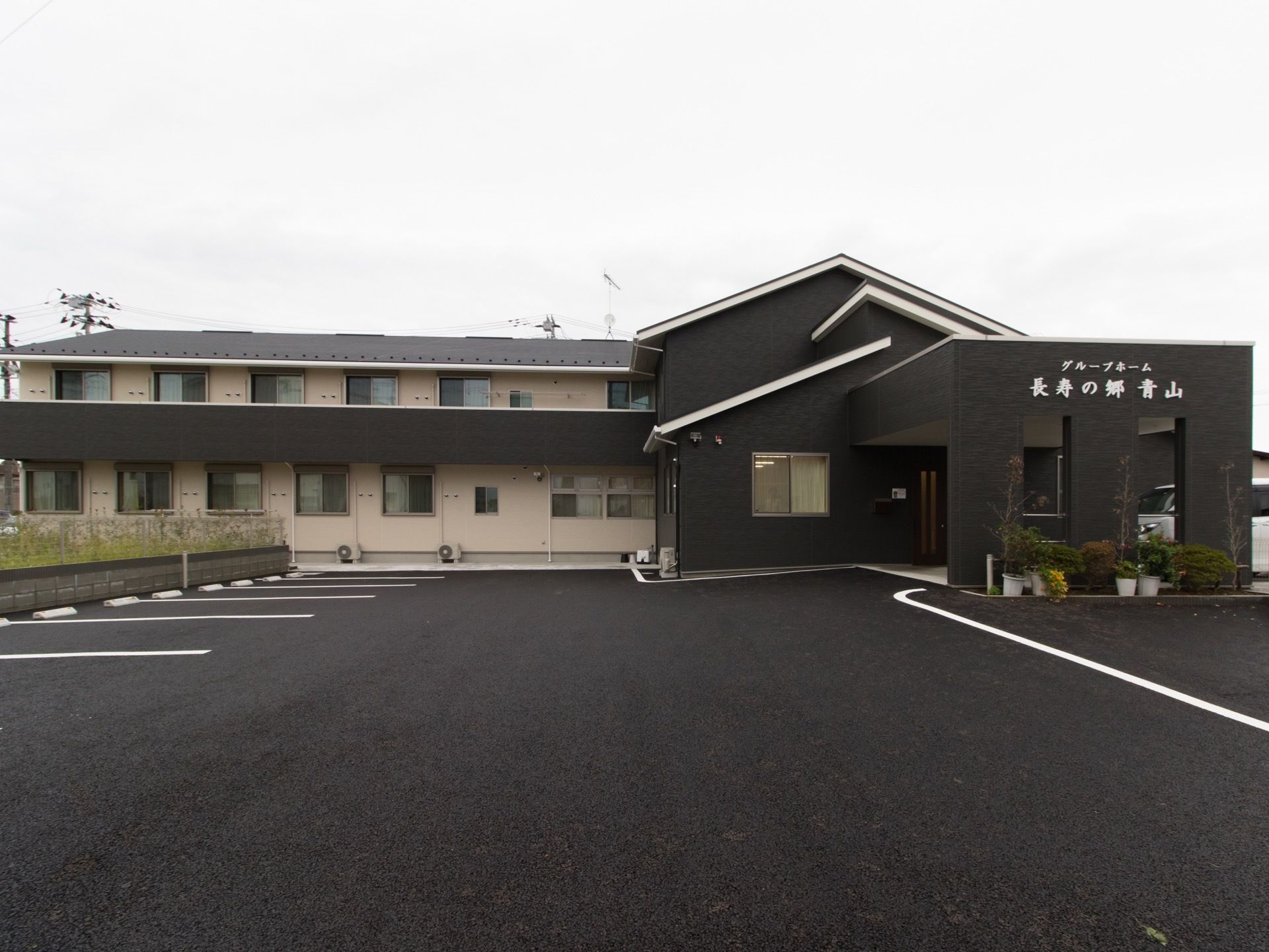 焦げ茶色を基調としたベージュ色とのツートンカラーの２階建ての外観である。建物前には駐車スペースを設けている。外壁には、白色で施設名がある。