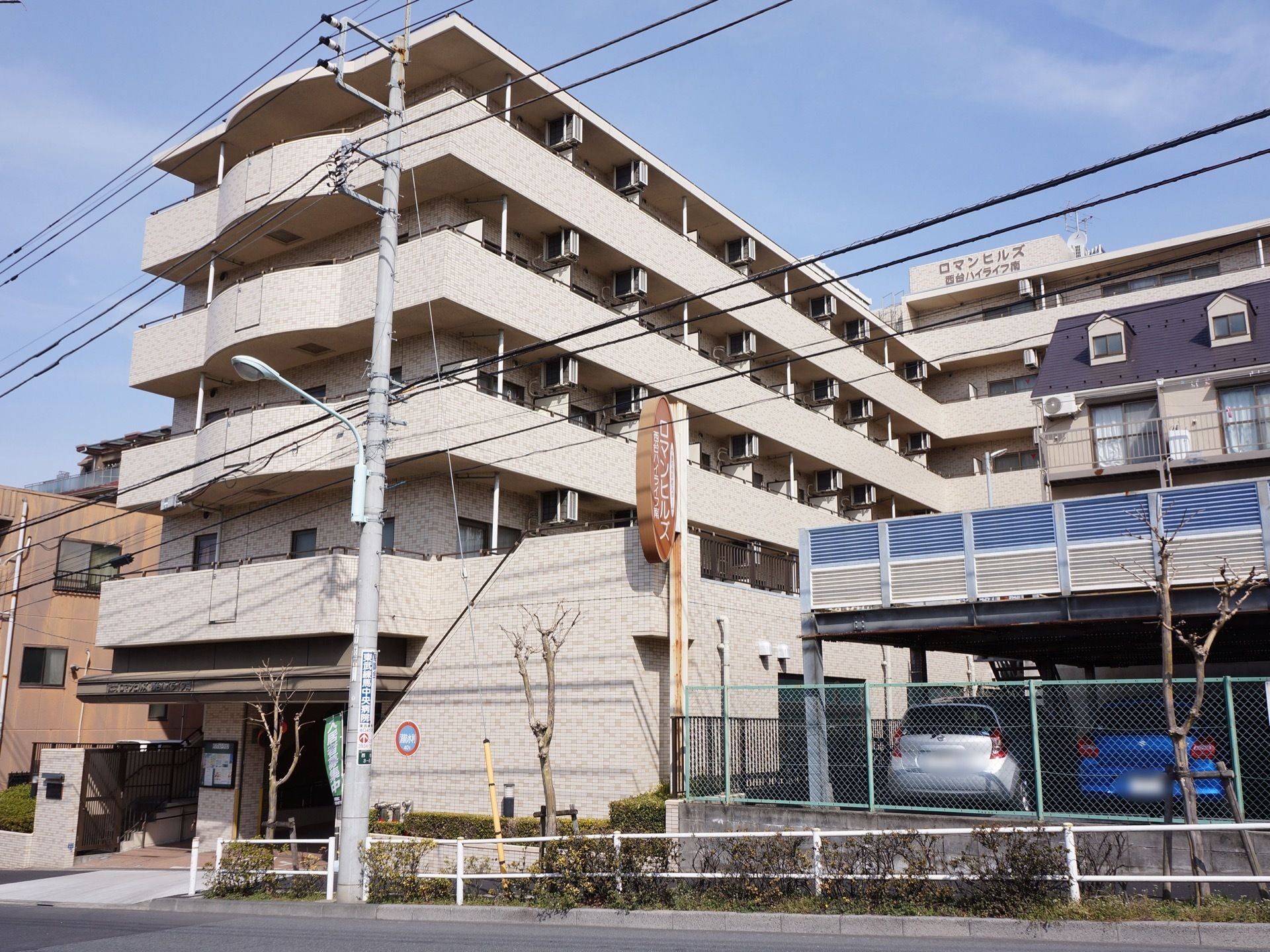 鉄筋コンクリートの５階建。最上階に施設名の看板あり。歩道から近い場所にも看板を設け目印となっている。