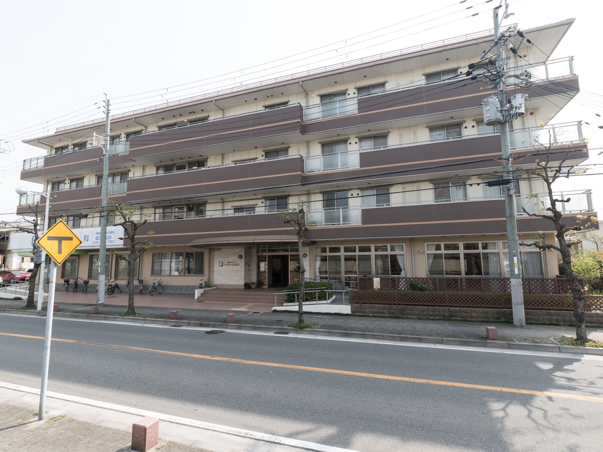 鉄骨造の４階建ての建物。温かみのある色合いが特徴で、居室にはベランダが設けられている。１階にはウッドデッキがあり、共有サロンと繋がっている。