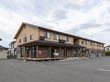 １階がこげ茶色で、２階が茶色い外壁の２階建ての建物がある。１階の縁側に洗濯物が干してあり、スロープが設置されている。