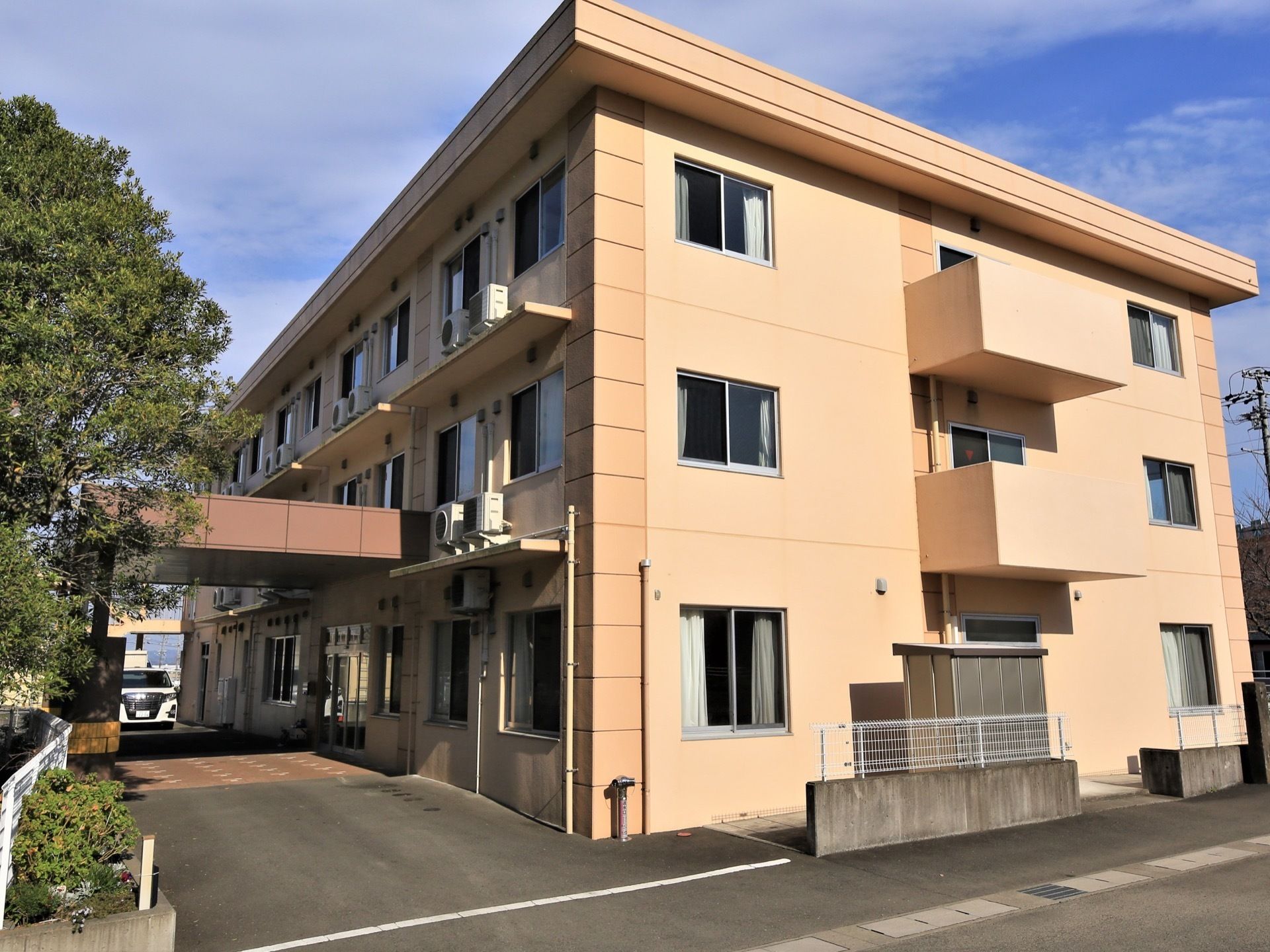 建物は３階建て構造になっており、中央を通る廊下をはさんで左右に居室が並んでいる。外壁には全ての部屋の分エアコンの室外機がある。