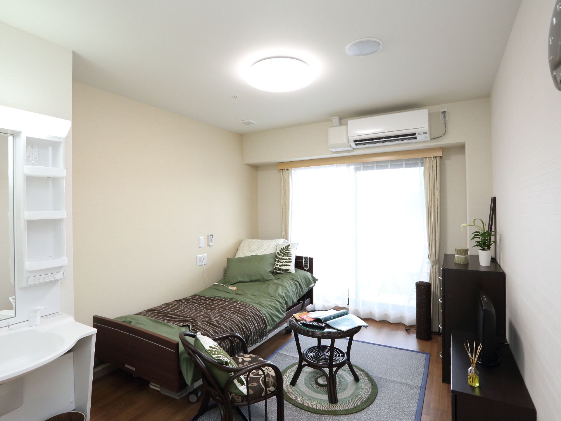 居室の窓からは、日差しが入り明るい部屋になっている。インテリアは持込が可能。柵の付いたベッドがあるので安心です。