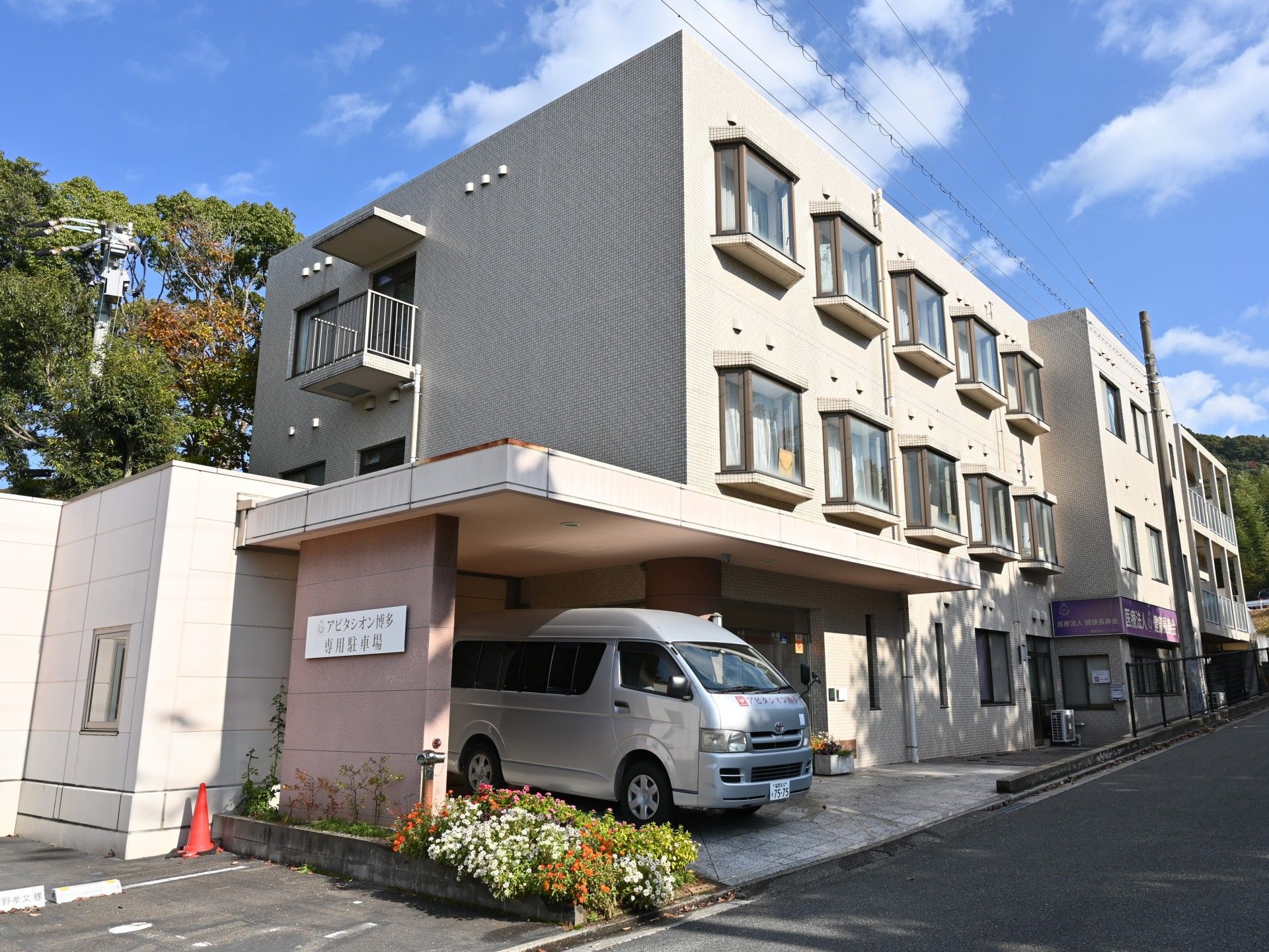 ３階建てで、ベージュ色の壁である。建物の道路側に各部屋の窓が設置されている。玄関そばに専用の駐車場が完備されている。