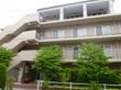 施設の建物は４階建てで、柔らかなアイボリーの外壁である。各部屋にバルコニーがあり、安全そうな非常階段があるのも見える。