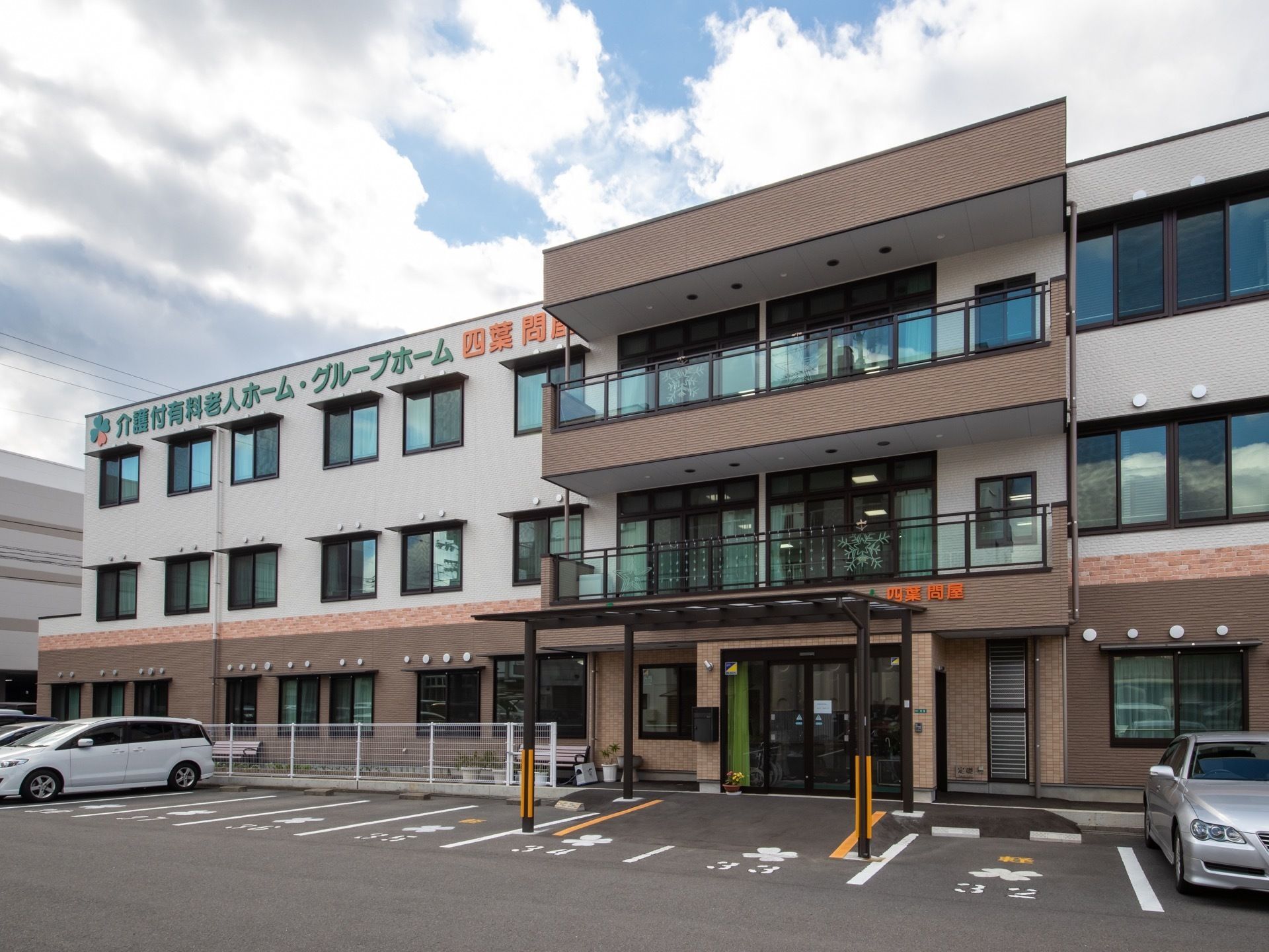 白とブラウンで統一された３階建ての大きな建物である。エントランスの前には駐車スペースがあり広々としている。