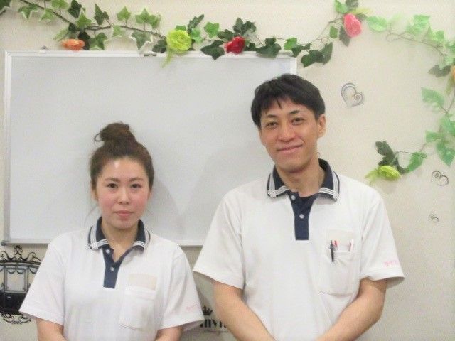 揃いのポロシャツを着た職員ふたりがカメラを見て微笑んでいる。