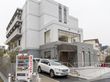 白を基調としている、清潔感のある建物。駐車場も完備。玄関には階段だけでなく、手すり付きのスロープも設置されている。