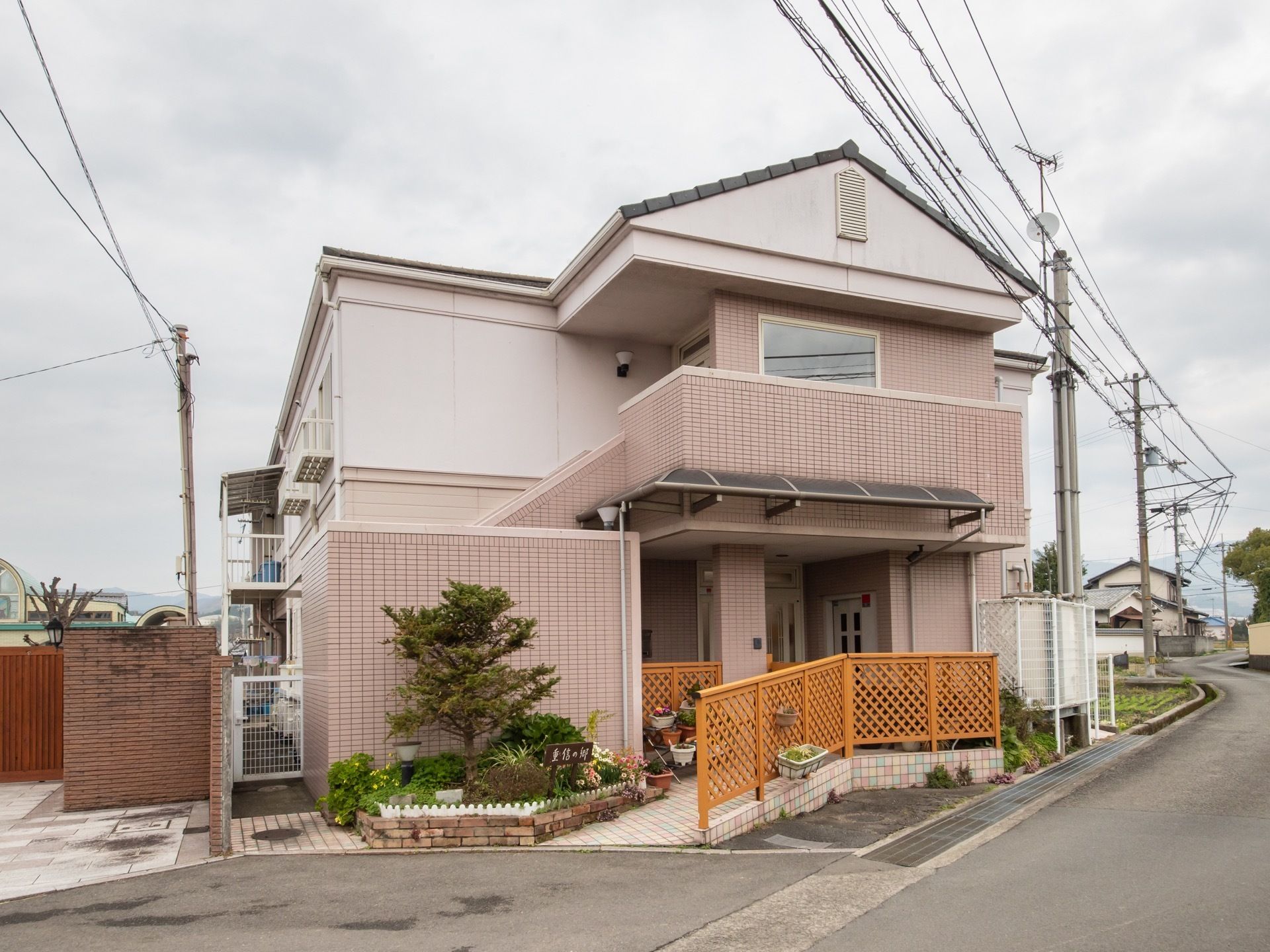 ピンク色の外壁がアットホームで、一軒家のような見た目である。周りは住宅地となっており、閑静な環境である。