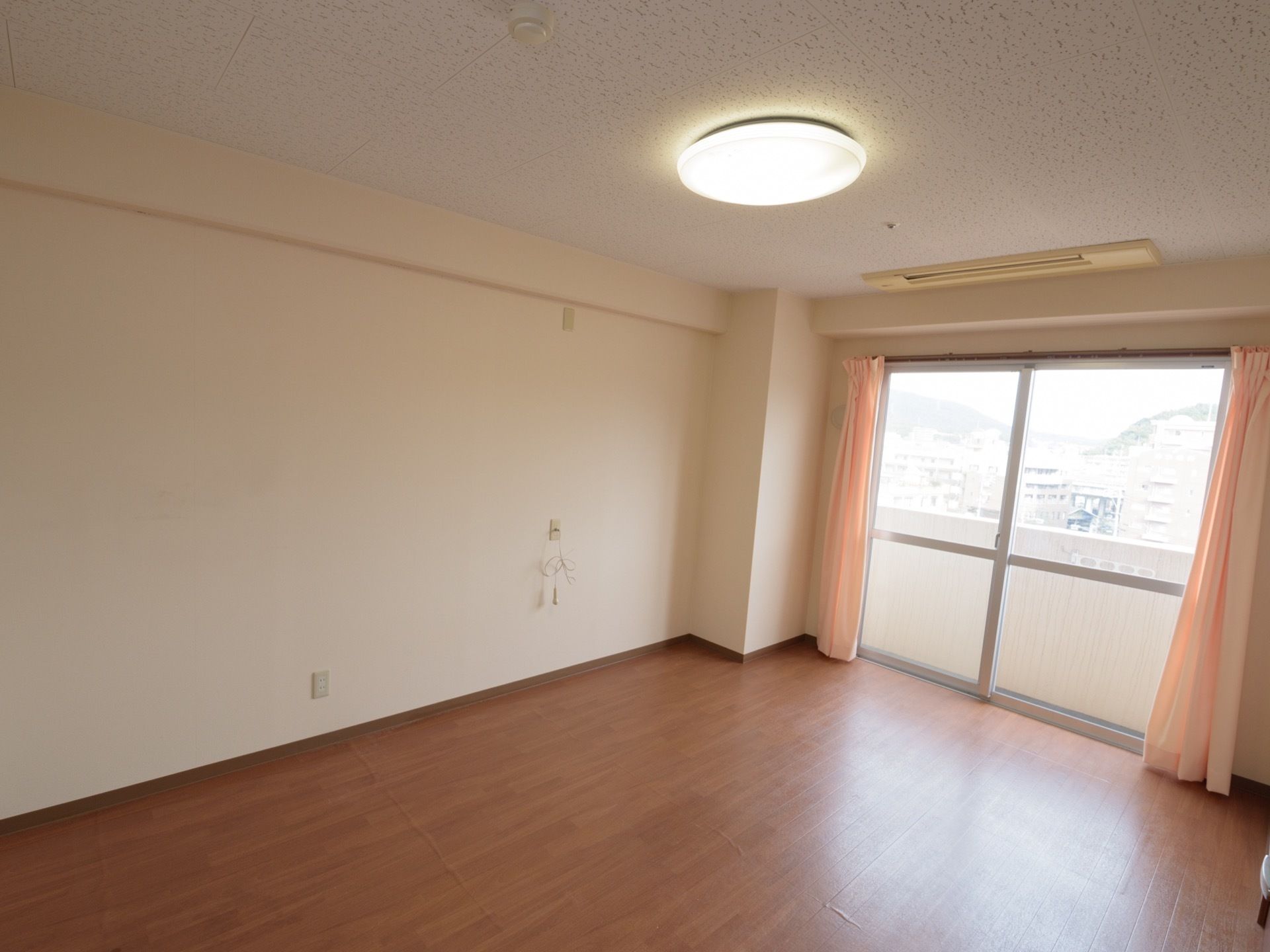 居室には大きな掃き出し窓がある。窓の外にはベランダが付いている。壁にはナースコールが取り付けられている。
