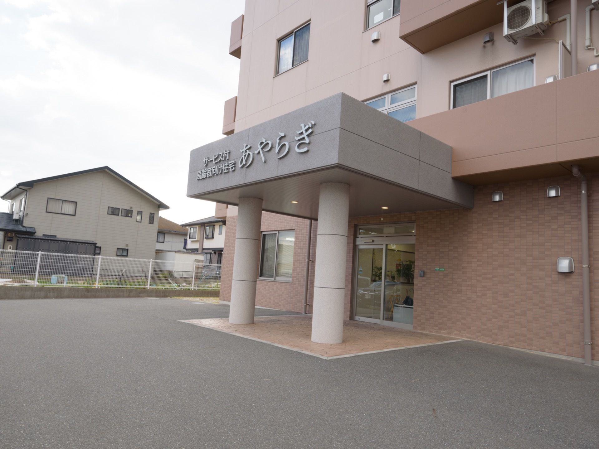 玄関前は障害物がなくすっきりとしている。屋根部分には施設名が大きく記されている。近くまで車をつけることができる。