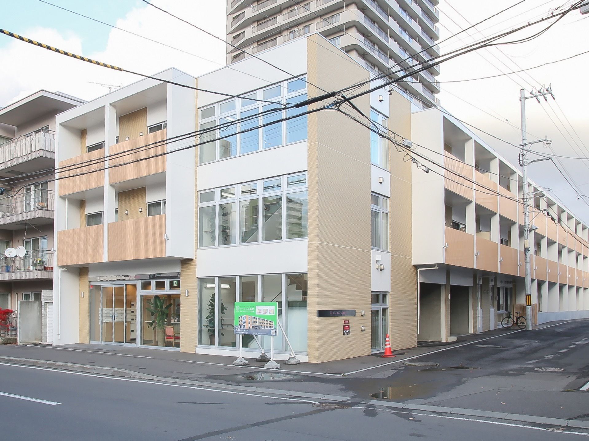 白とナチュラルブラウンで統一感のある、３階建ての施設建物である。窓が多く、外からでも施設内の明るさを感じることができる。