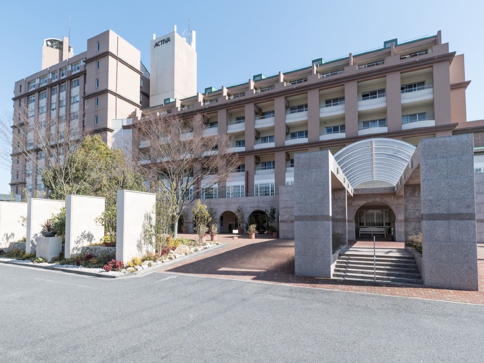 居室総数300室の大きな建物。外観はリゾートホテルのような高級感のあるデザインである。正面玄関のアプローチの階段には手すりが設置されている。