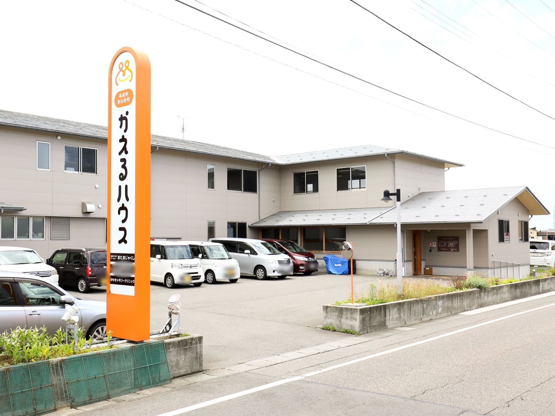 道路沿いに施設名が書かれた看板が設置されている。敷地内にはアスファルトで舗装された駐車場が完備されている。