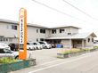 道路沿いに施設名が書かれた看板が設置されている。敷地内にはアスファルトで舗装された駐車場が完備されている。