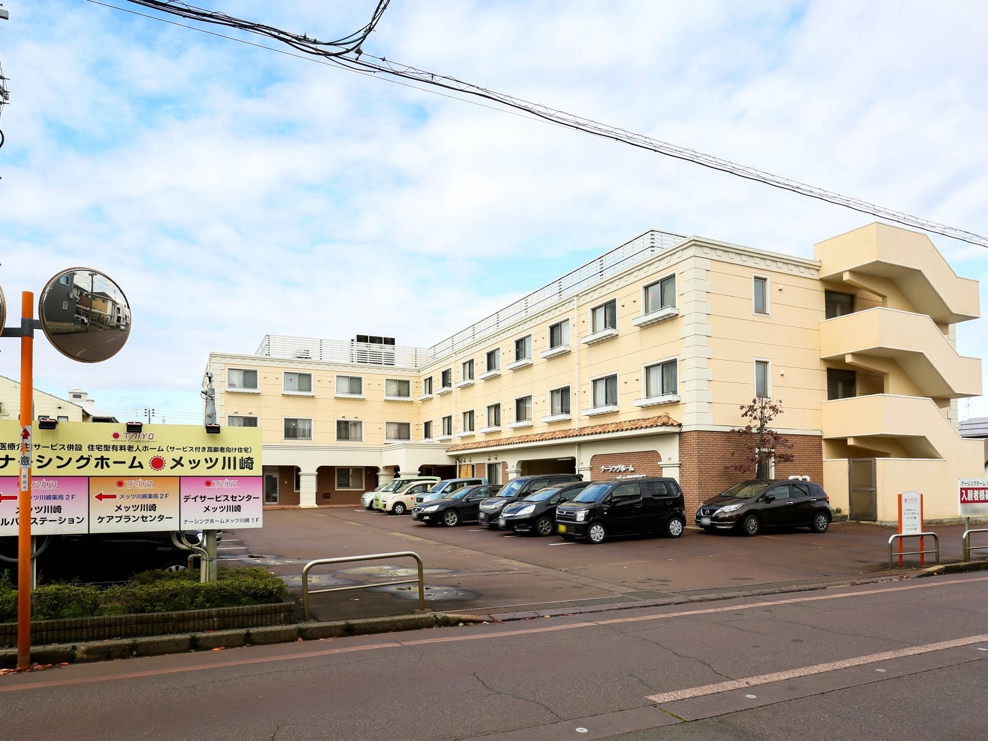 道路に面した敷地である。敷地の境目には、銀色のガードが設置されている。また、道路にはカーブミラーもある。