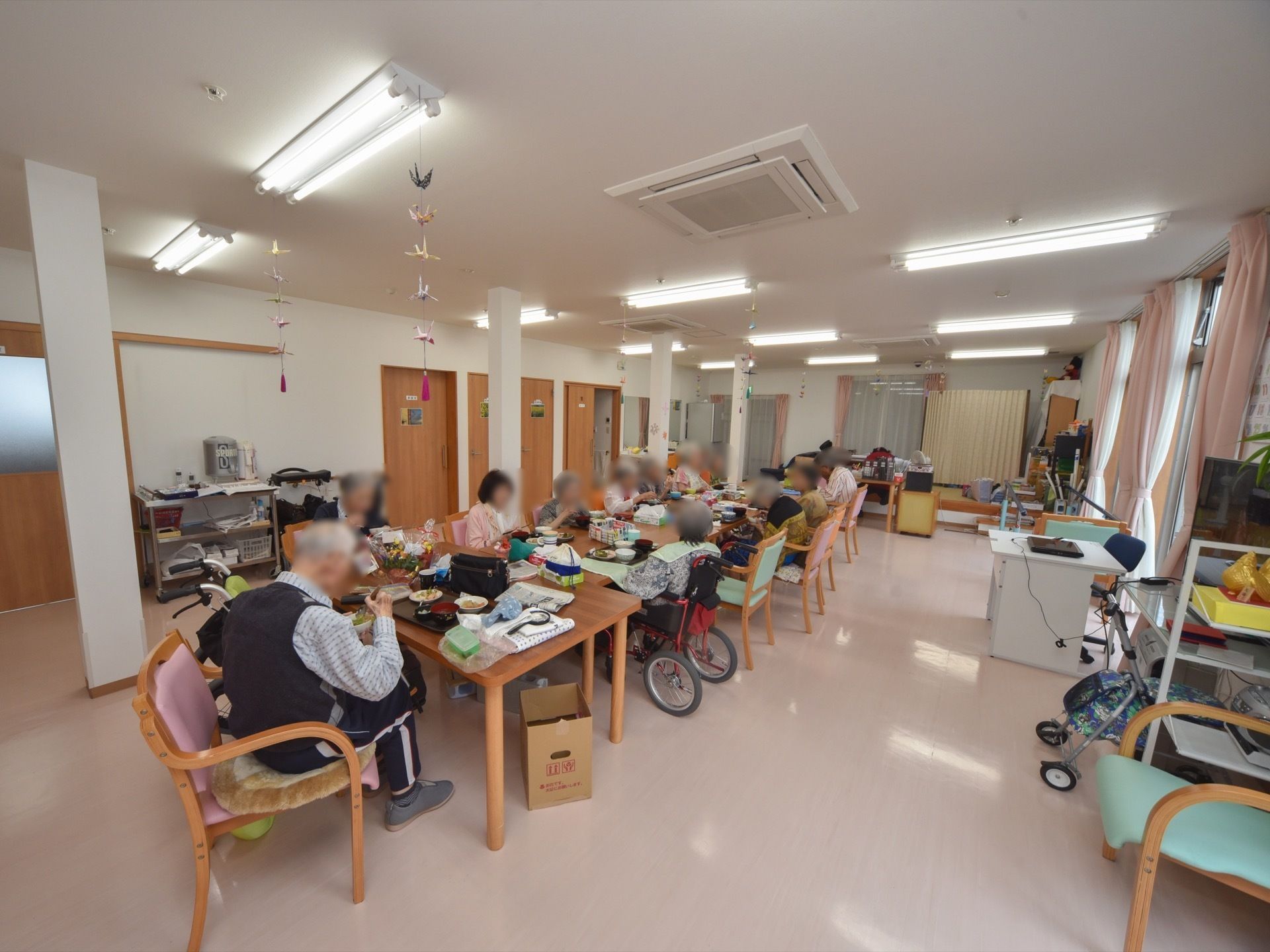 いくつかのテーブルをつなげて長テーブルとして利用している。いすの人も車いすの人も一緒に並んで食事をしている。