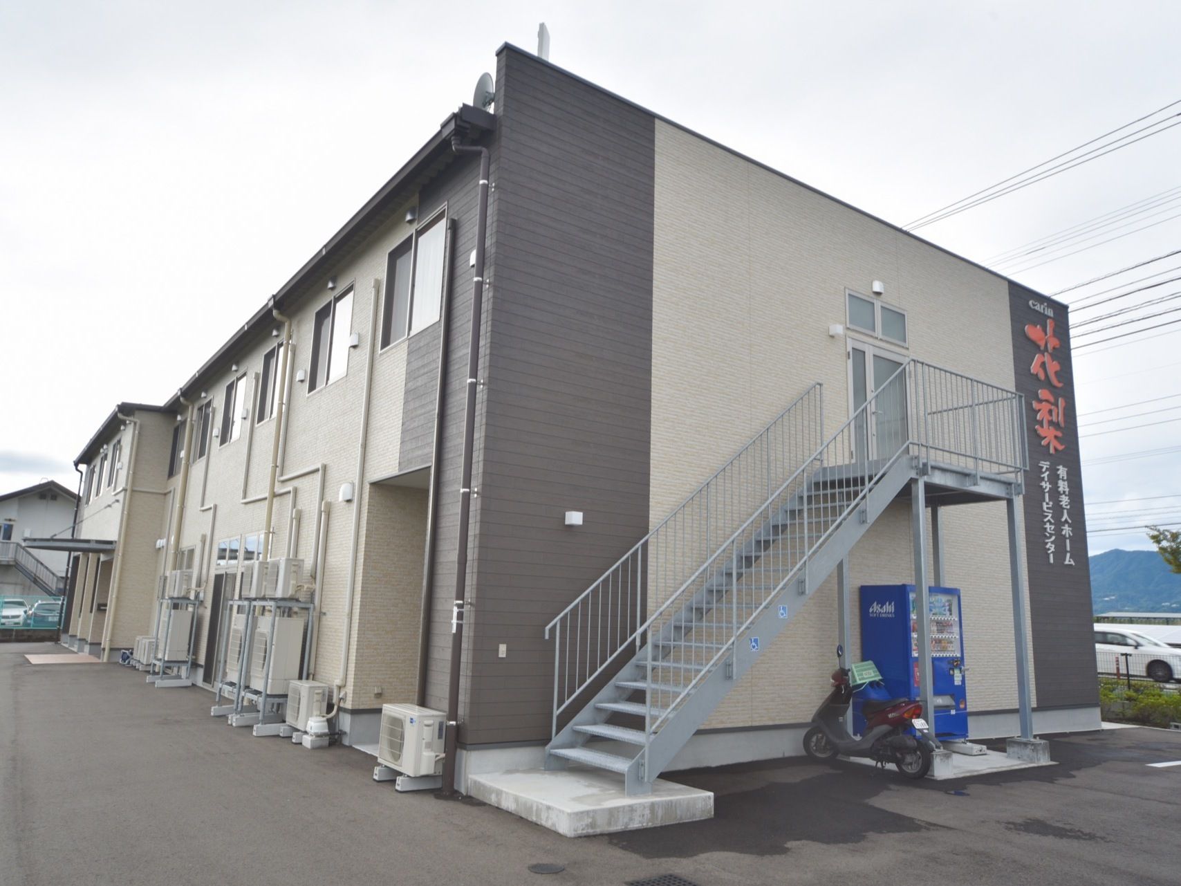2階建ての施設である。2階からの非常階段が外に設置してあり、階段の下の空間に自動販売機が設置してある。