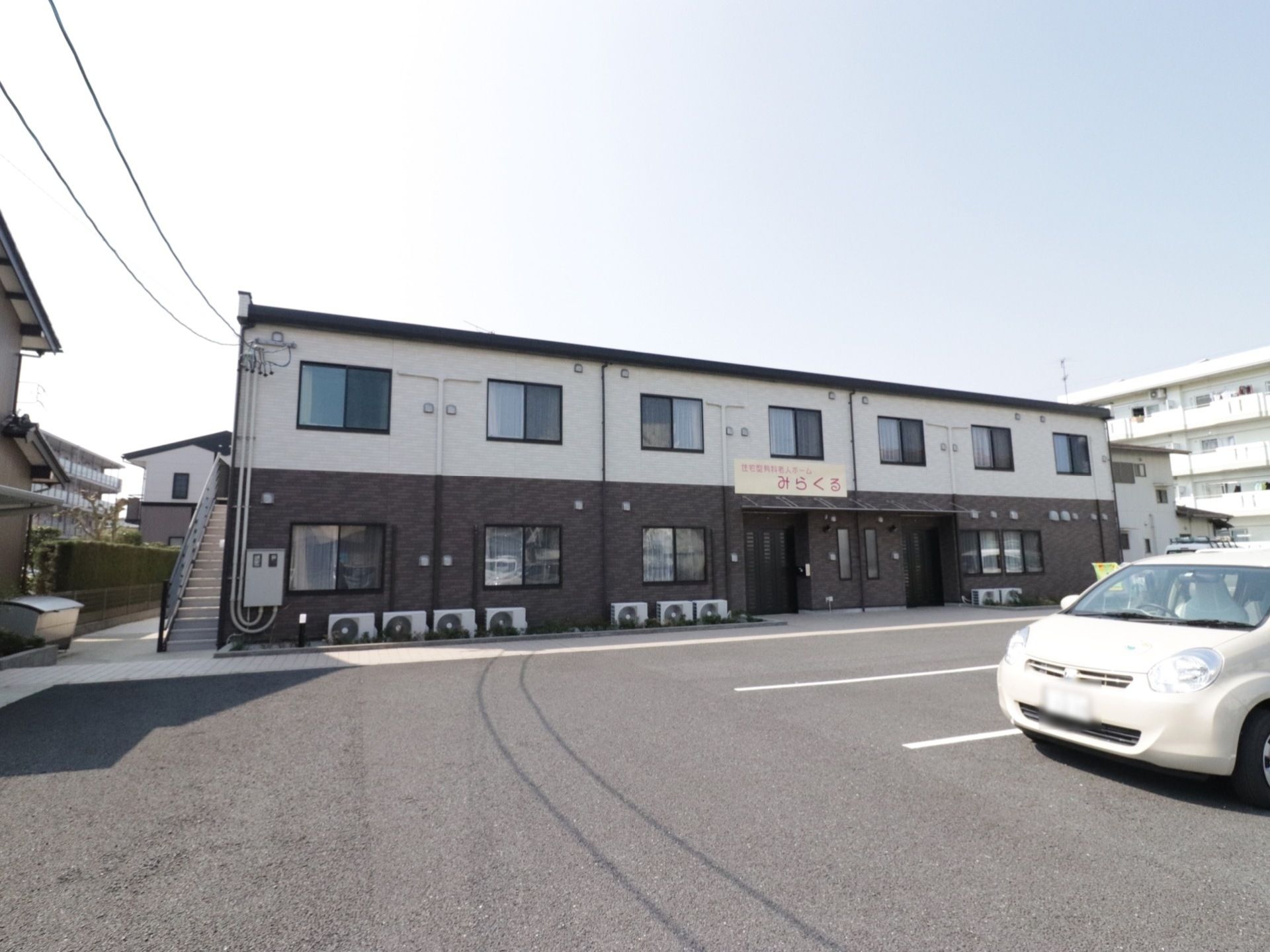 2階建てのシンプルな外観の施設の前には広いスペースがあり車を数台駐車できる。施設には非常用に外階段も設置してある。