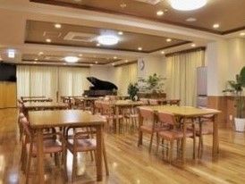 ４人掛けテーブルが置いてある。壁一面が掃き出し窓である。床はフローリング。部屋の隅にはグランドピアノが置いてある。