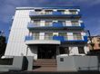 施設の外観。アパート風の4階建ての建物である。外壁は白色ベースで、ベランダや屋上の壁は青色をしている。