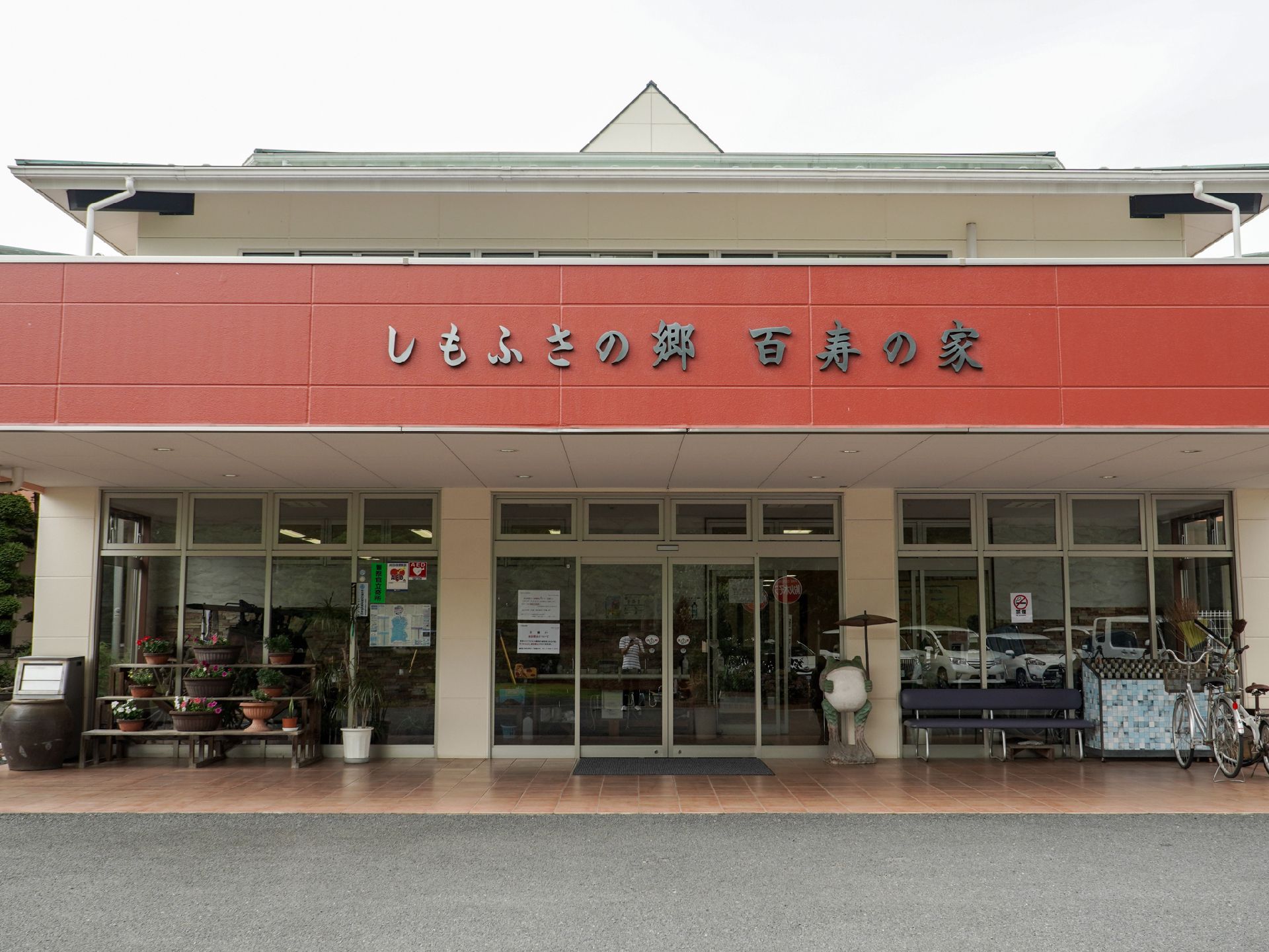 曇り空と側面がガラス張りになっている赤い看板の建物