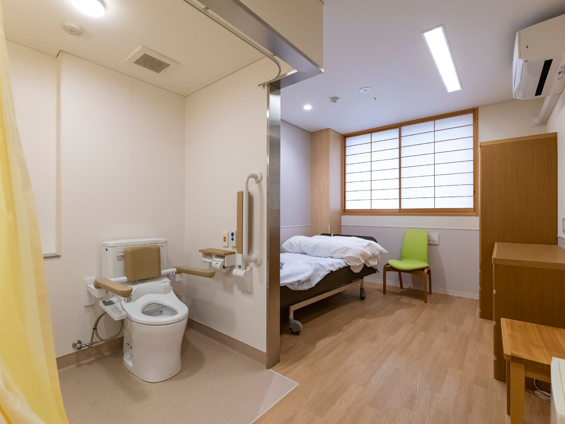壁を隔ててトイレとベッドが並んでいる部屋