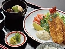 エビフライやサラダが盛られたお皿の横に漬物や吸い物が置かれたお盆。