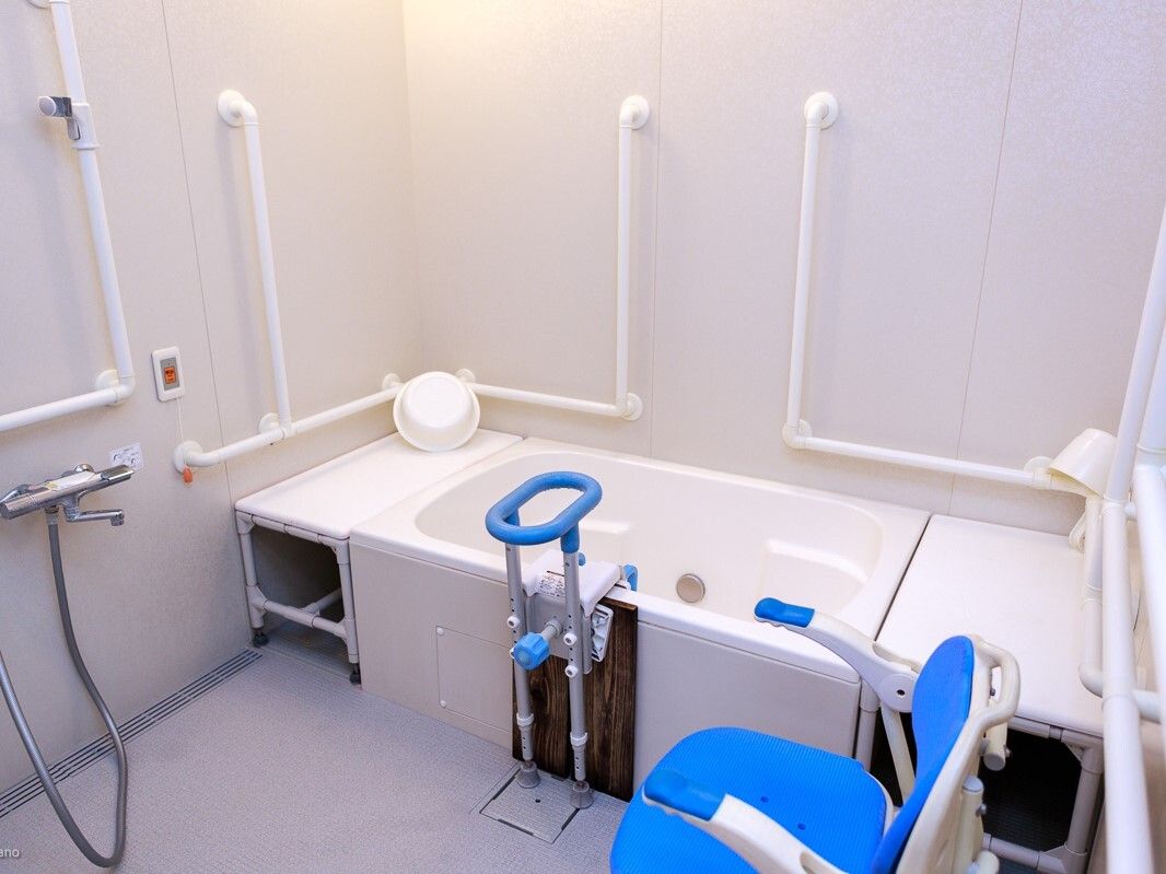 フラワーアレンジメントをしている眼鏡をかけた高齢男性と手伝っているエプロンを付けた女性スタッフ。