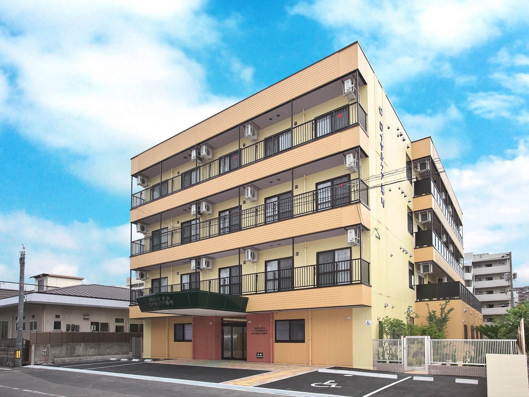 ベージュ系の外壁の建物は4階建てで各フロアにベランダがあり、車寄せが付いている。