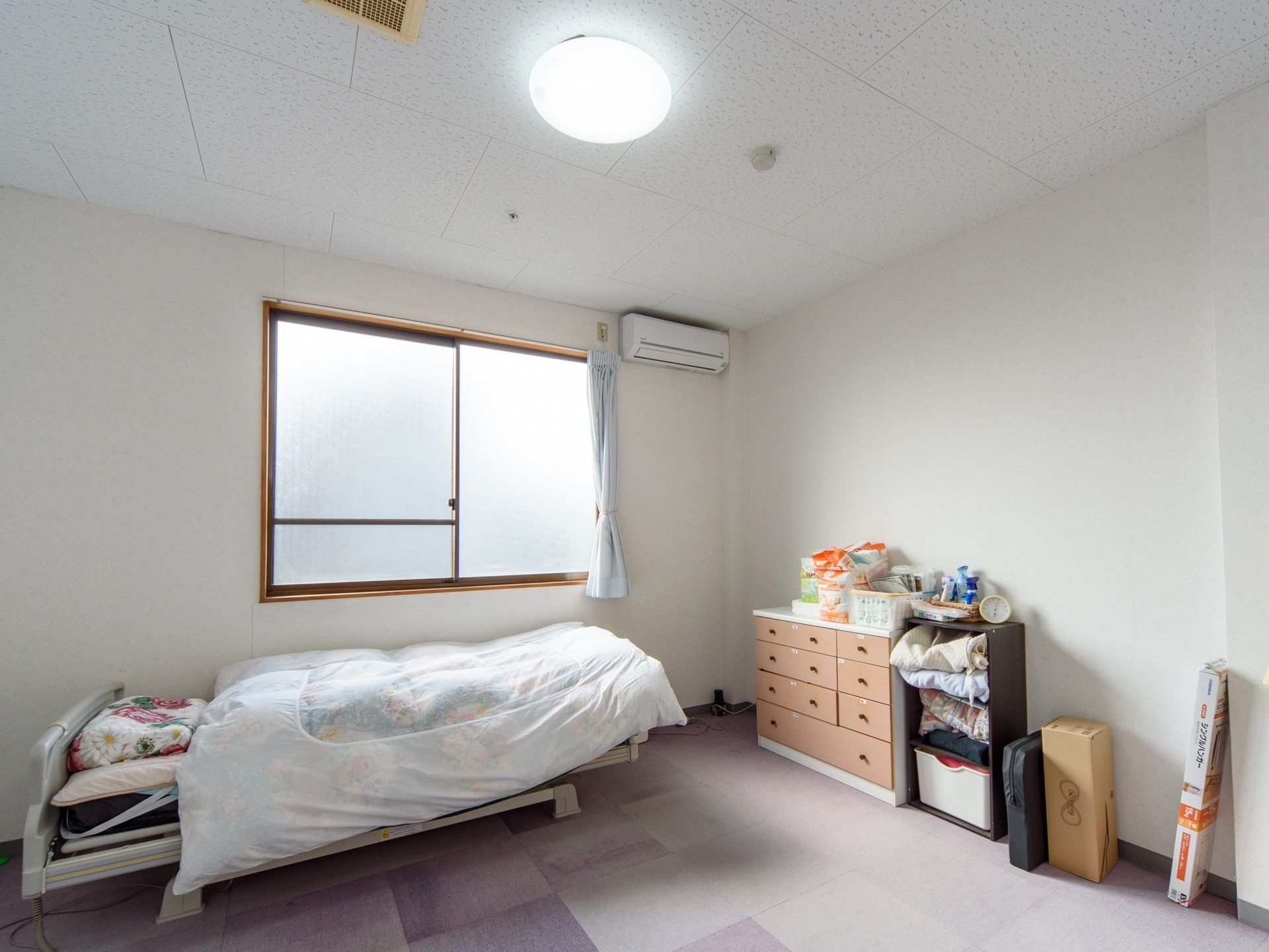 カーペット敷きのすっきりした居室は空調完備となっている。ベッド周囲にスペースを確保できる広さを備えている。