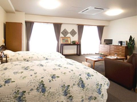 ベッドが２つ置かれた広い居室。ソファや机、シェルフなどが置かれており、２人でも快適に過ごすことができる。