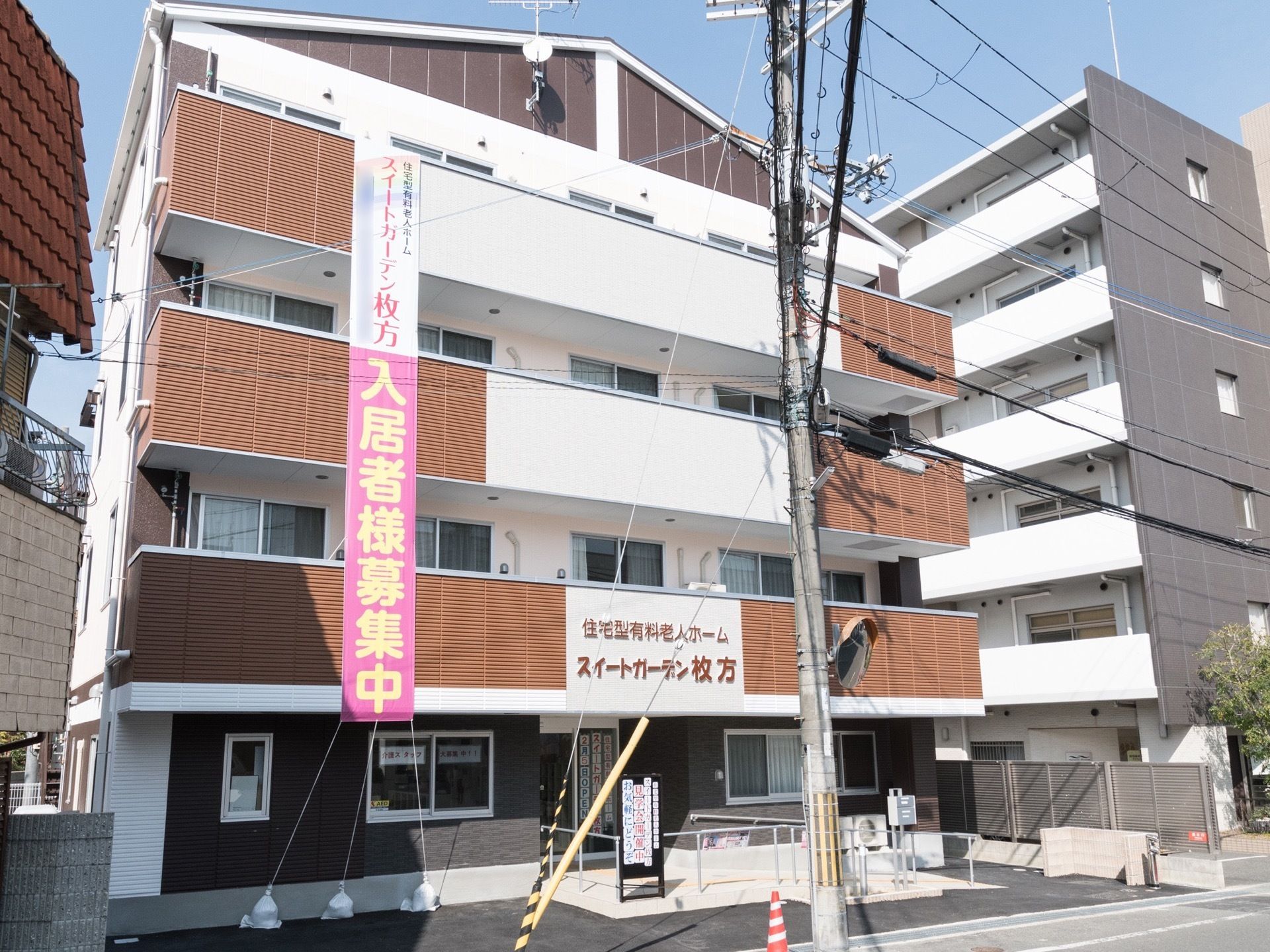 ４階建ての三角屋根の建物で、入り口の上に大きな看板が付いている。４階のベランダから、入居者募集の垂れ幕が下がっている。