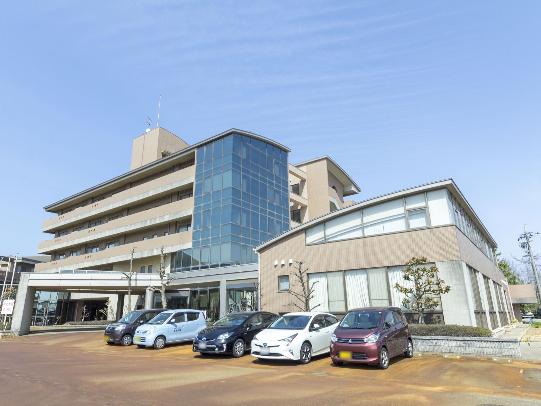 併設されている建物の前に駐車スペースがあり、何台かの車が停まっている。広々としていて、緑の多い敷地内である。
