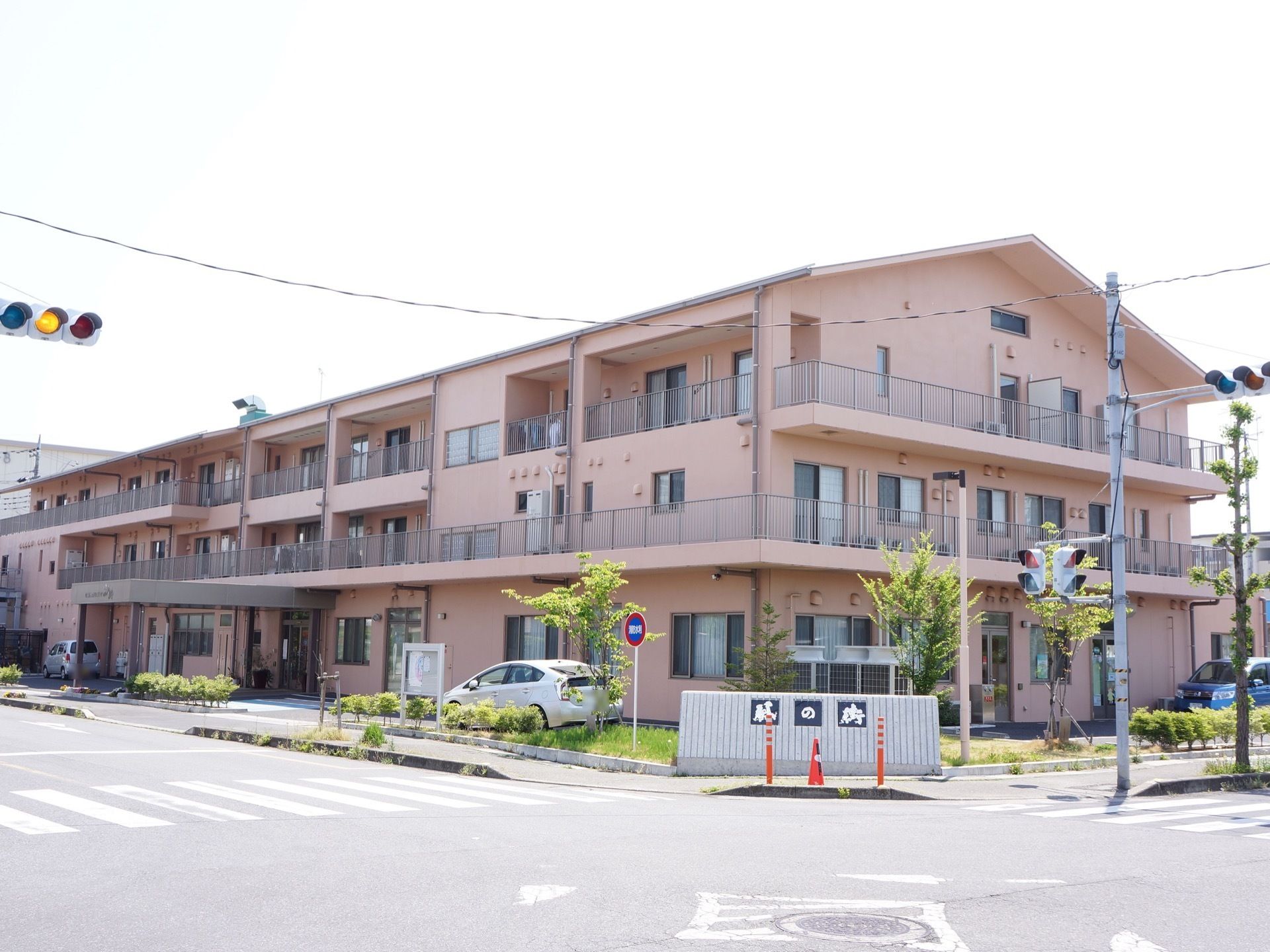 角地に建物が建っている。建物の周りは太陽を遮るものがないので、日当たりがよい。淡いピンク色の３階建ての造りである。