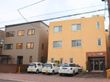 施設は３階建ての凹凸の無い四角い建物である。１階の入り口部分はレンガ調に装飾されている。建物の前に車が停められている。