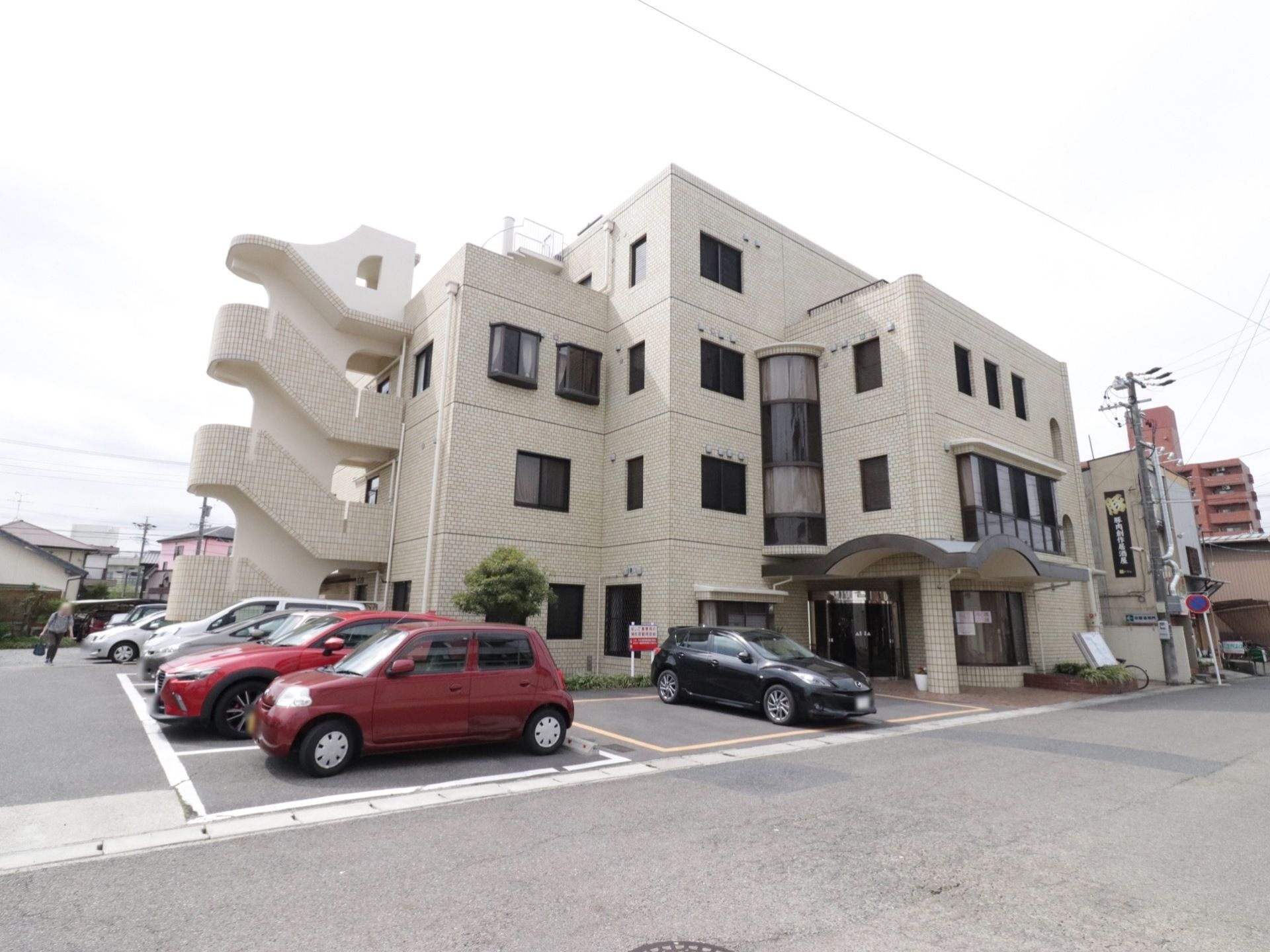 4階建ての施設で、隣に大きな駐車場が完備されている。玄関前には大きな屋根がついている。施設前に花壇がある。