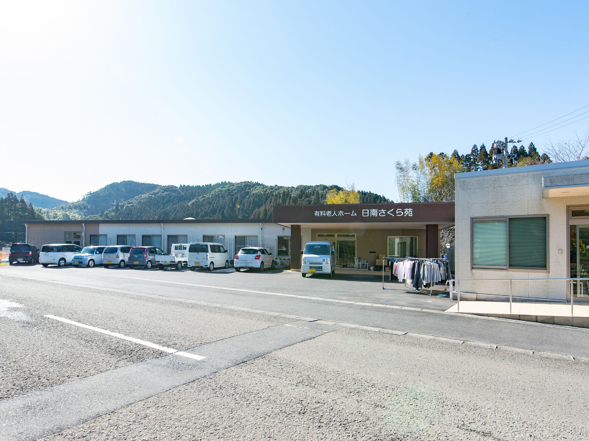 青空と緑濃く連なる山々を背景に立地する１階建ての施設である。ご利用いただきやすい料金体制でさまざまな介護ケアを提供する。