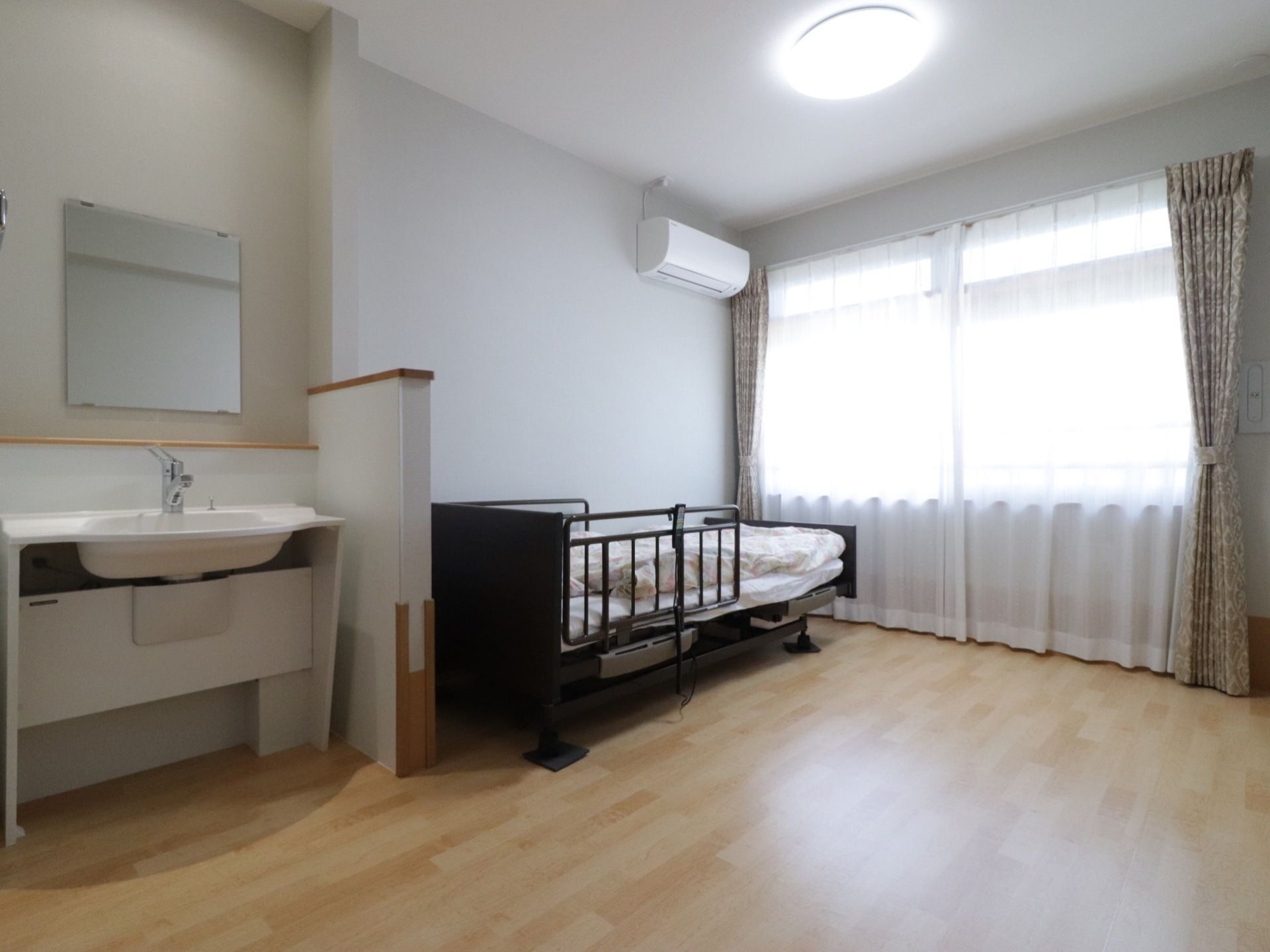 洗面台とベッドの間には、背の低い壁が設置されている。ベッドが置いてあっても、部屋は十分な広さがある。