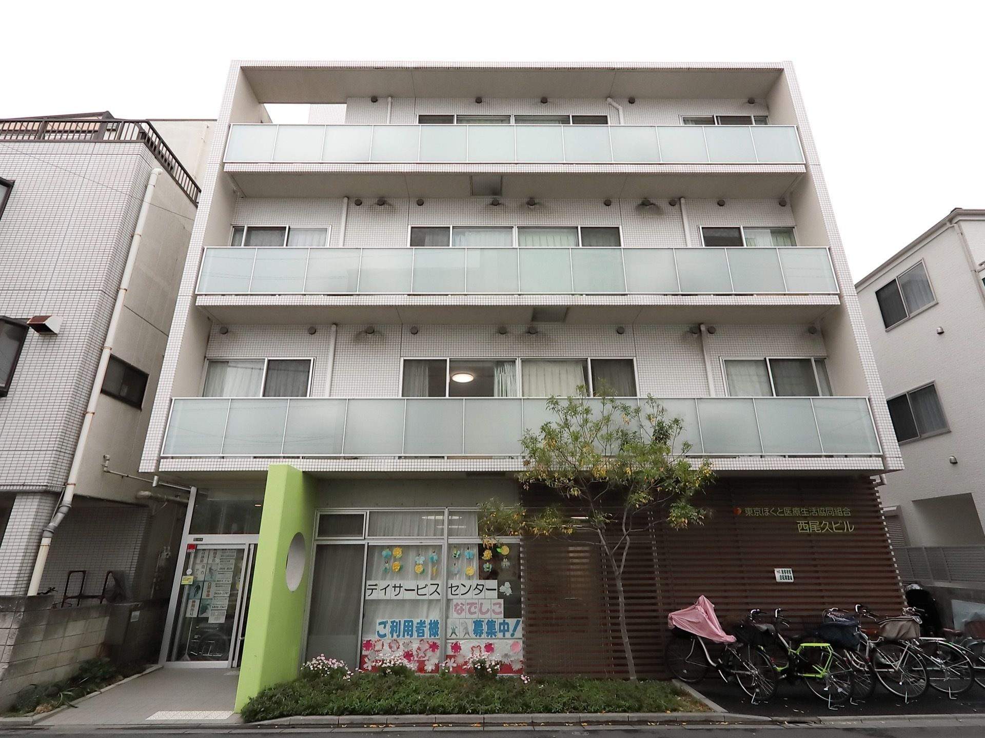 白色を基調とした、シンプルな施設である。1階部分がデイサービスセンターになっている。グリーンの壁が印象的。
