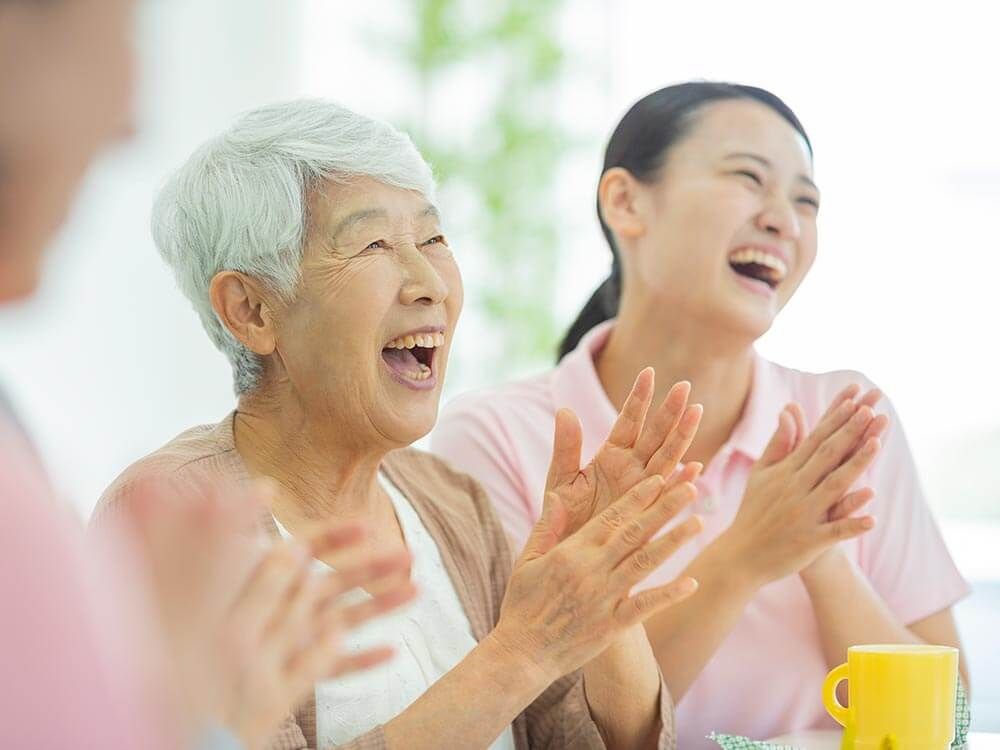 拍手をする高齢女性と女性スタッフ