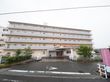 施設は５階建てで、敷地内には広い駐車スペースが設けられている。玄関前には、オレンジ色の屋根も設置されている。