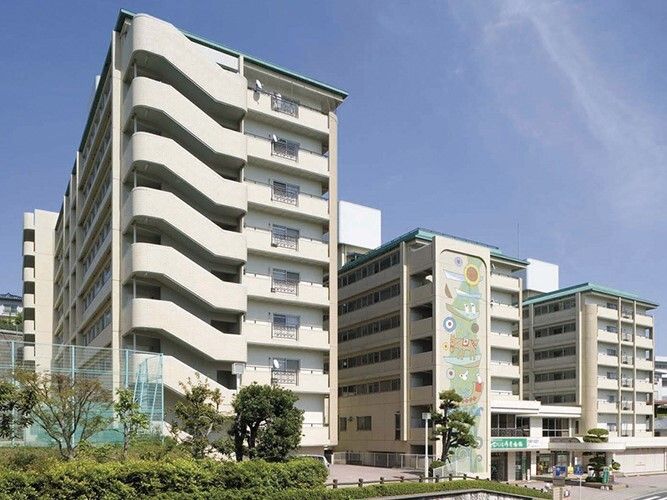 外壁の一部にイラストが描かれている大きなマンションのような建物。白い外壁で日当たり良好。