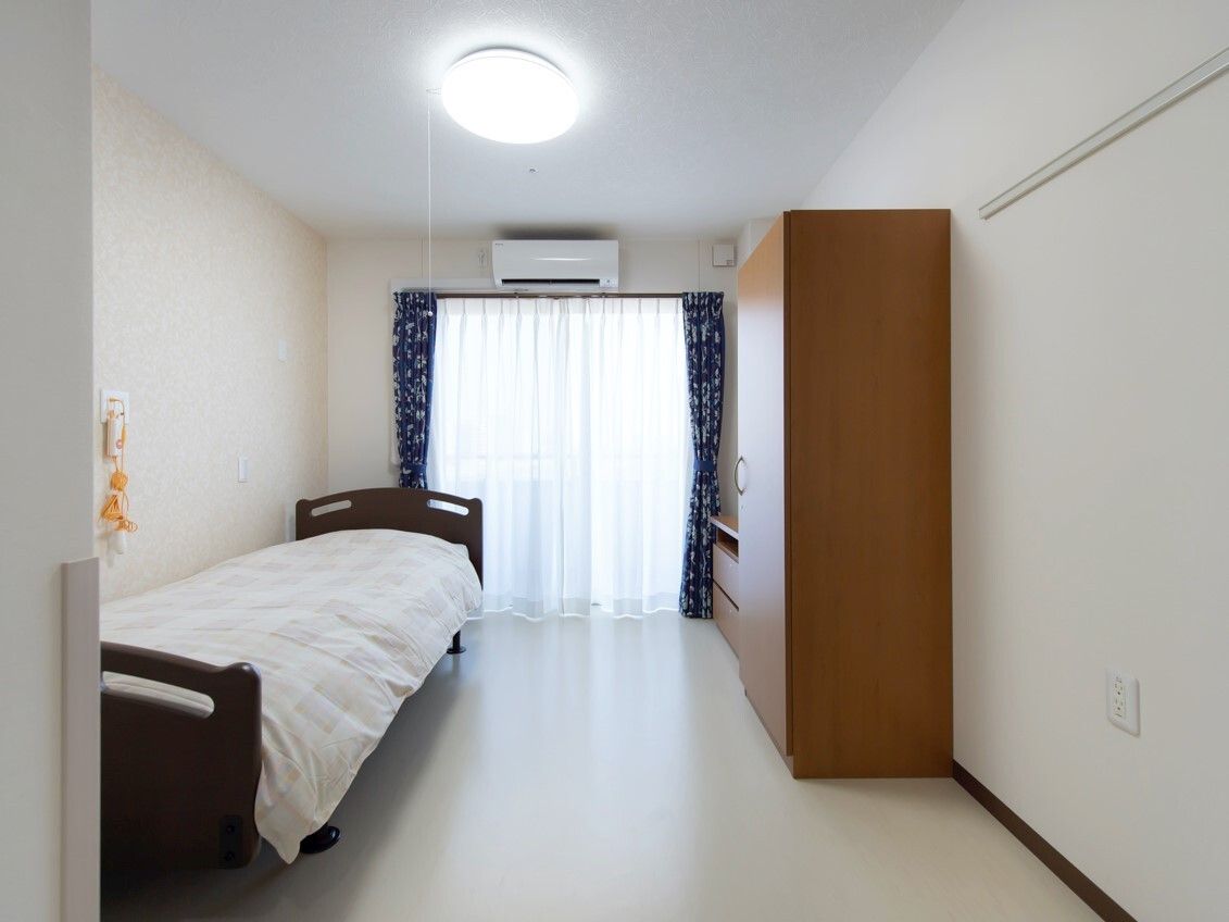 寝具付きのベッドが置かれ、クローゼットやエアコンが付いている部屋には緊急通報装置がある。